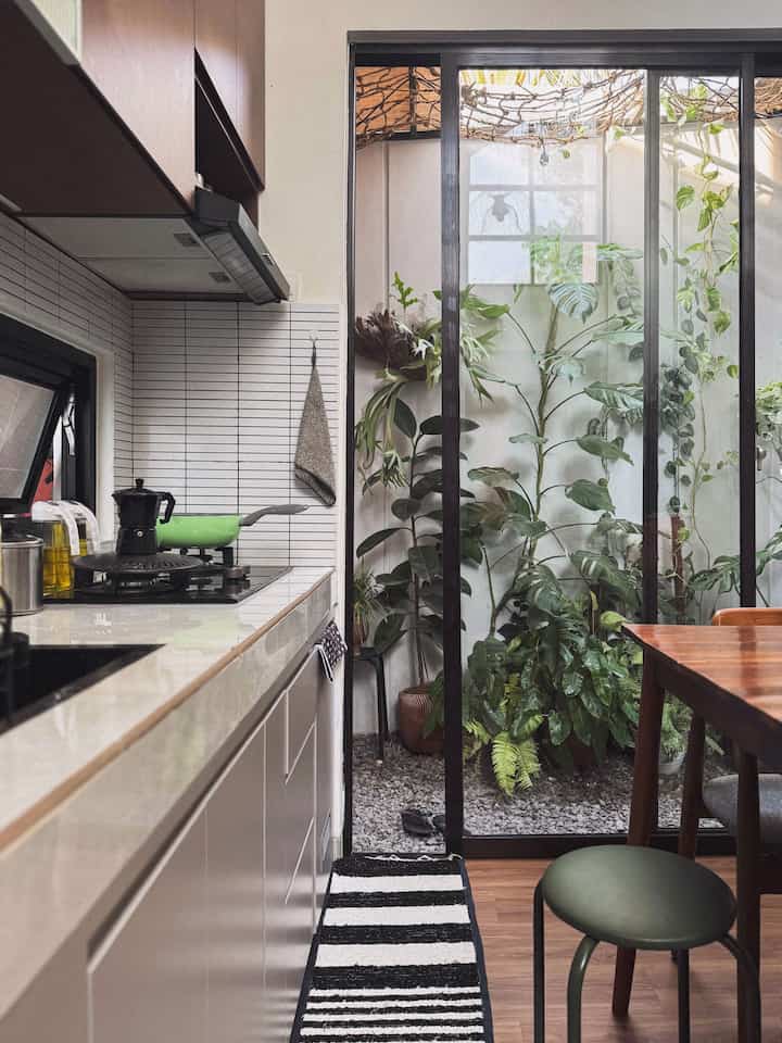 Beige and black toned small kitchen featuring green plants and wooden dining table in a natural atmosphere