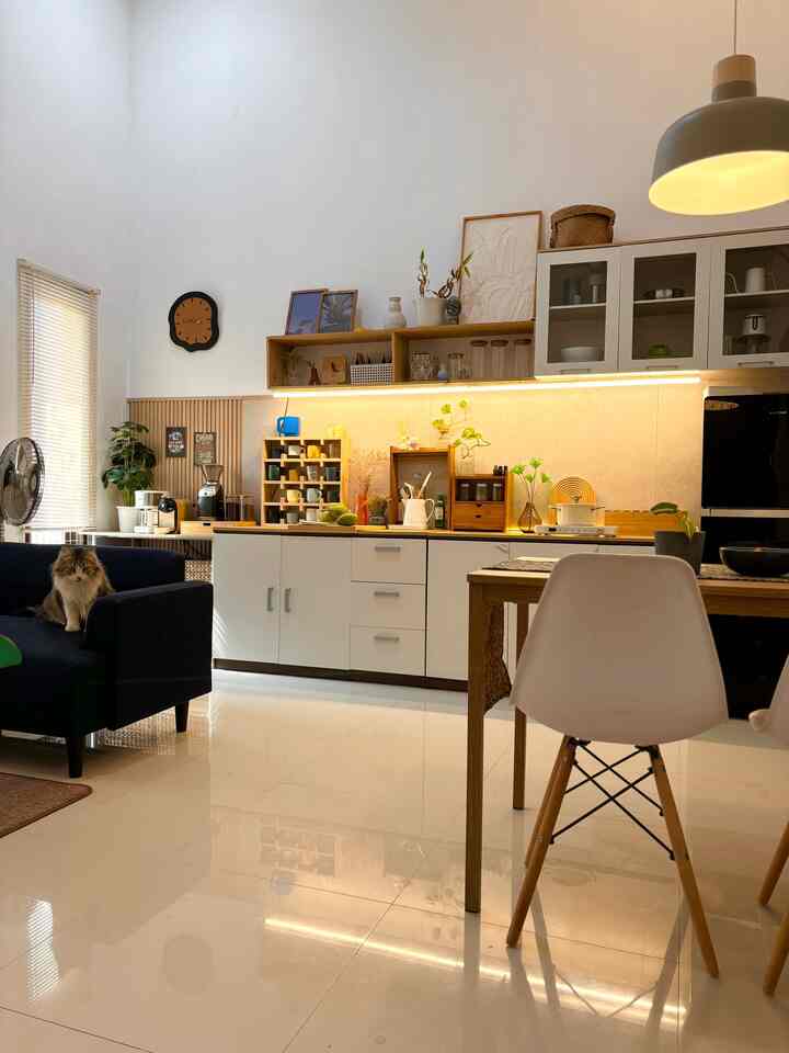 White and wood-tone kitchen and living room featuring a sofa with a cat, creating a cozy home cafe atmosphere