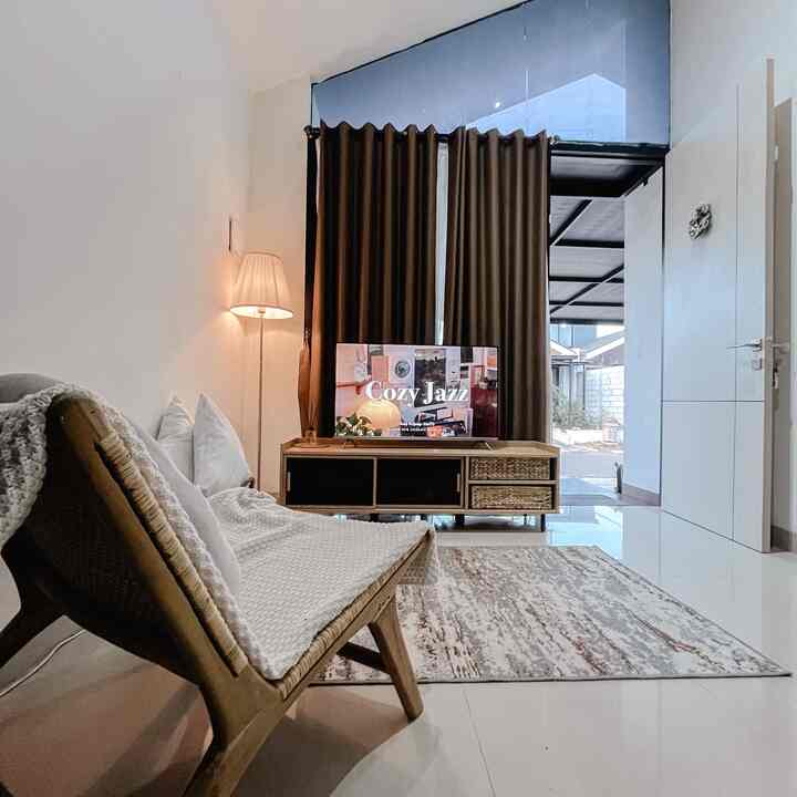 A white and brown toned single household living room featuring a wooden chair, carpet, and floor lamp in a cozy setting