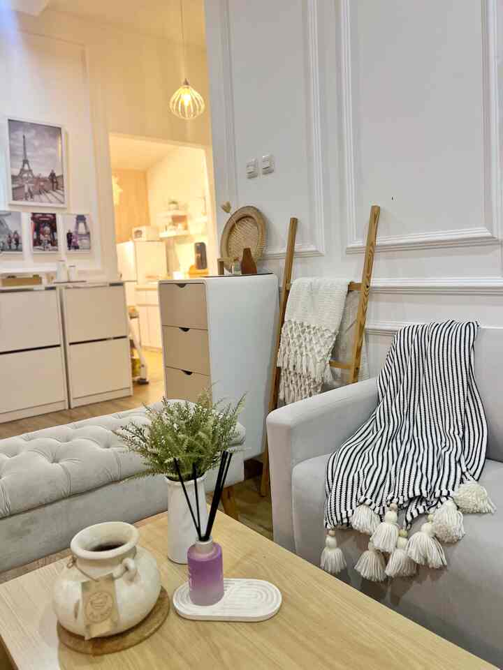 Bright beige and white toned living room featuring a sofa, wooden coffee table, and decorative plants with cozy atmosphere