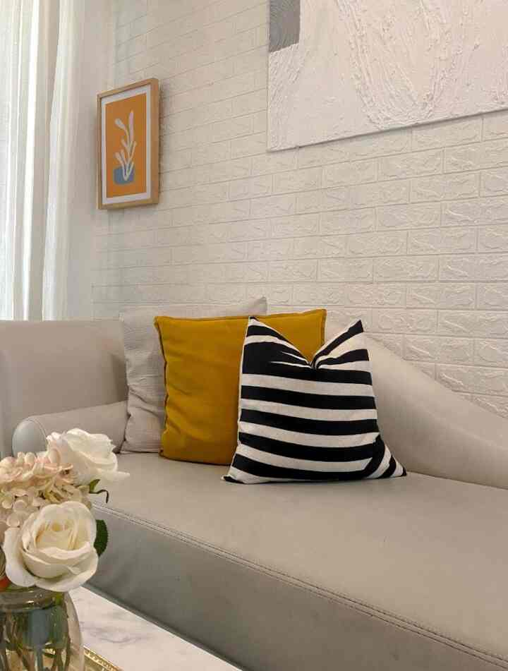 Living room with white walls and beige sofa featuring mustard and striped cushions in a cozy setting