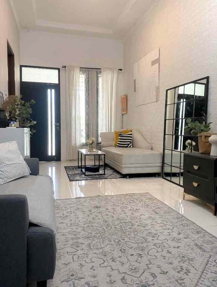 A white and monotone living room featuring simple sofas, carpets, tables, and a large mirror in a modern setting