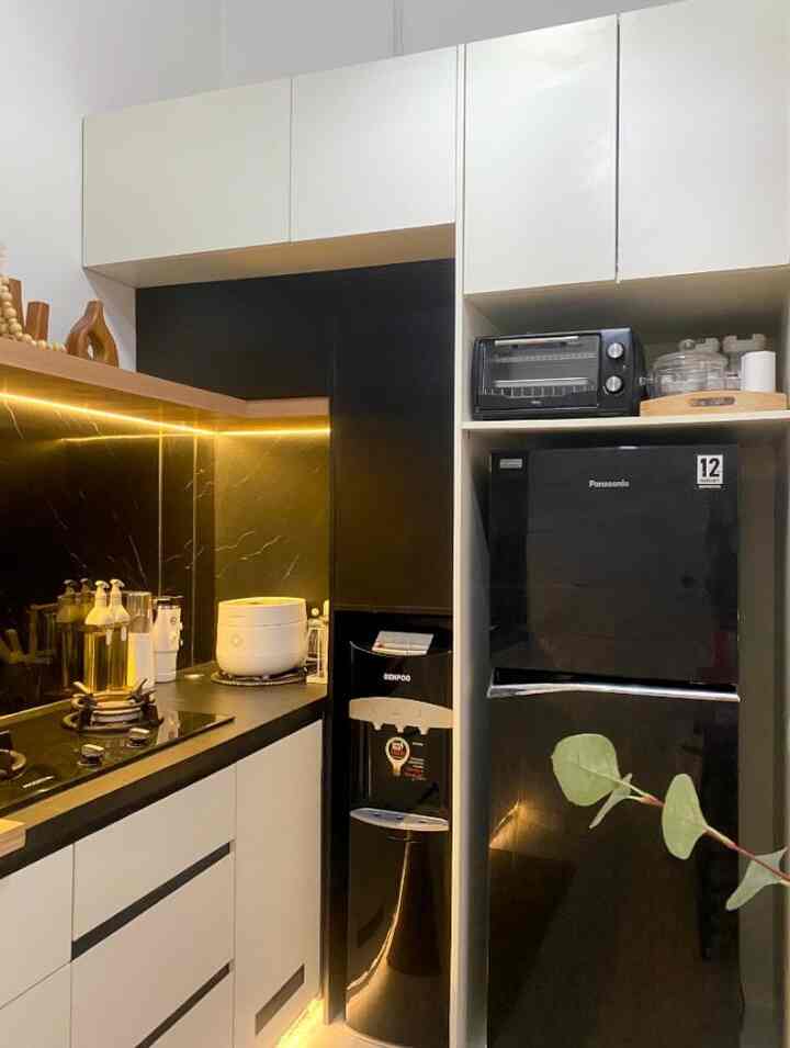 Black and white toned kitchen featuring a black refrigerator, water dispenser, and white upper-lower cabinets in a clean modern layout