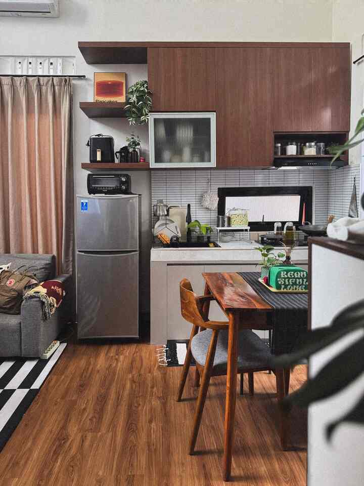 Brown wood tone and gray studio apartment kitchen-dining space featuring sofa and table with cozy atmosphere