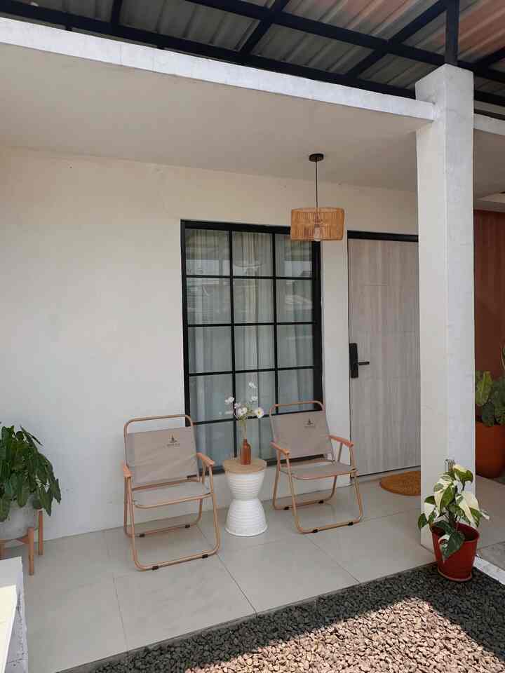 Beige and yellow toned balcony featuring two foldable outdoor chairs, a side table, and a rattan pendant lamp creating a cozy outdoor seating area