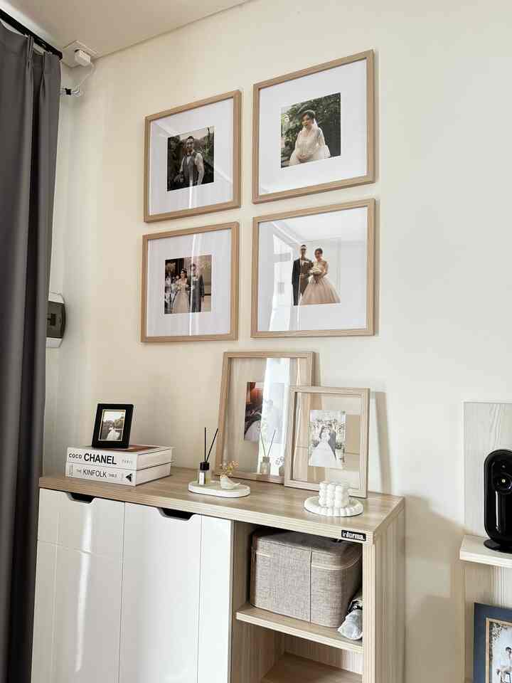 Minimal entrance space featuring white walls and wood-tone shoe cabinet, adorned with picture frames for a cozy atmosphere.