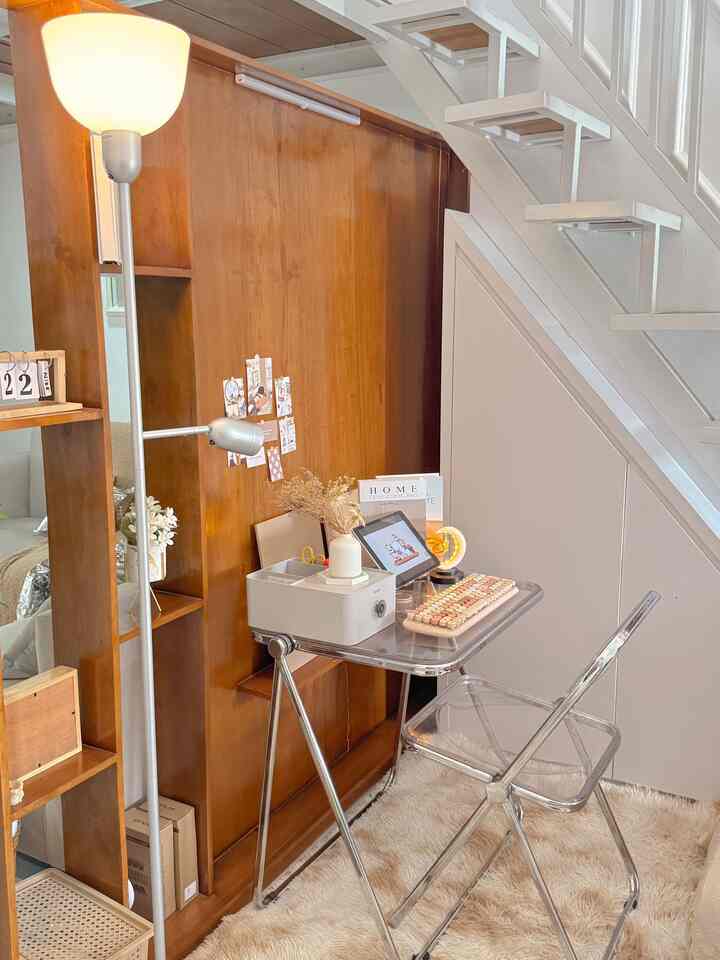 Warm wood tones and transparent furniture compose a folding home office in a compact studio space