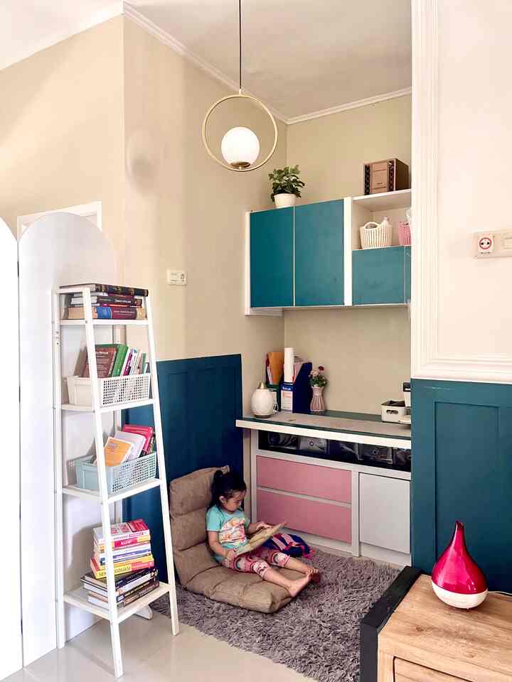 Beige and blue toned kids' room featuring a child reading on a floor cushion chair in a cozy nook