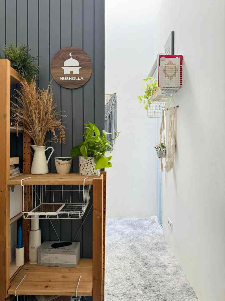 Cozy entrance space with white walls, wood tone storage unit, gray carpet, and various plants neatly arranged