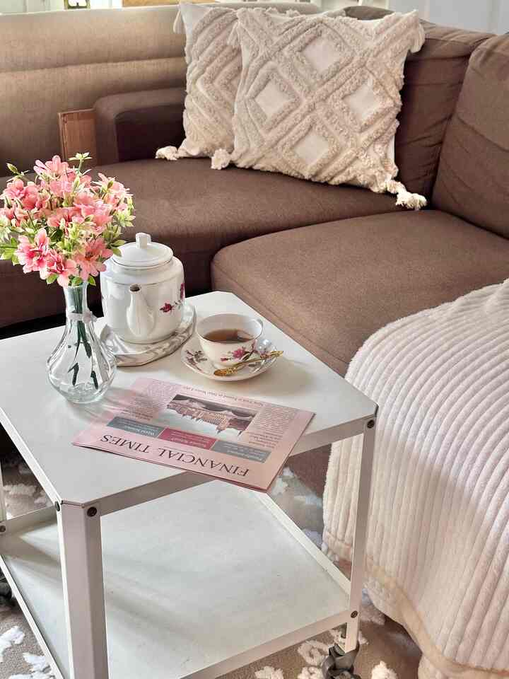 Brown-toned living room featuring a sectional sofa and white side table with teapot and cup creating a cozy atmosphere