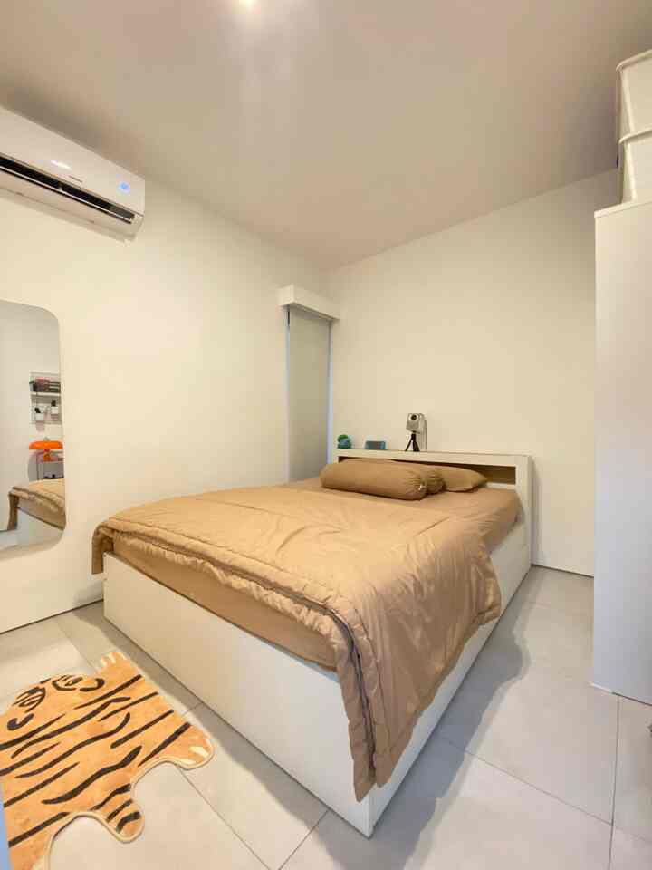 White walls and floors with beige bedding in a compact, tidy bedroom space