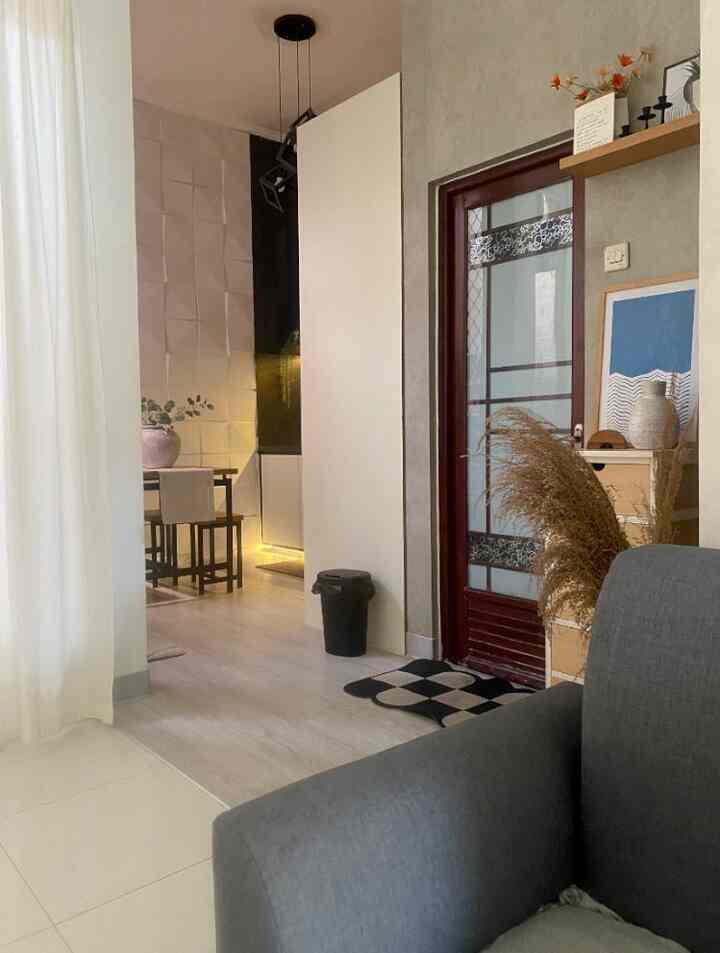 Gray and white toned living room featuring sofa by window with white curtains, a storage cabinet next to door, creating a cozy atmosphere