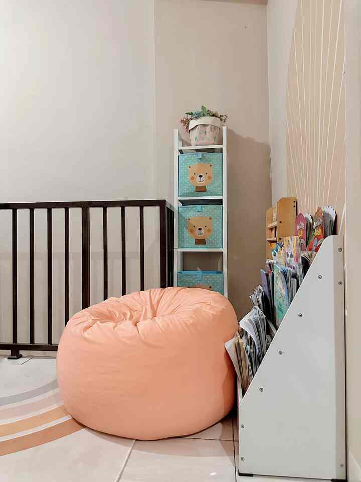 Cozy kids' space featuring a pink bean bag with white shelves and a bookshelf filled with children's books