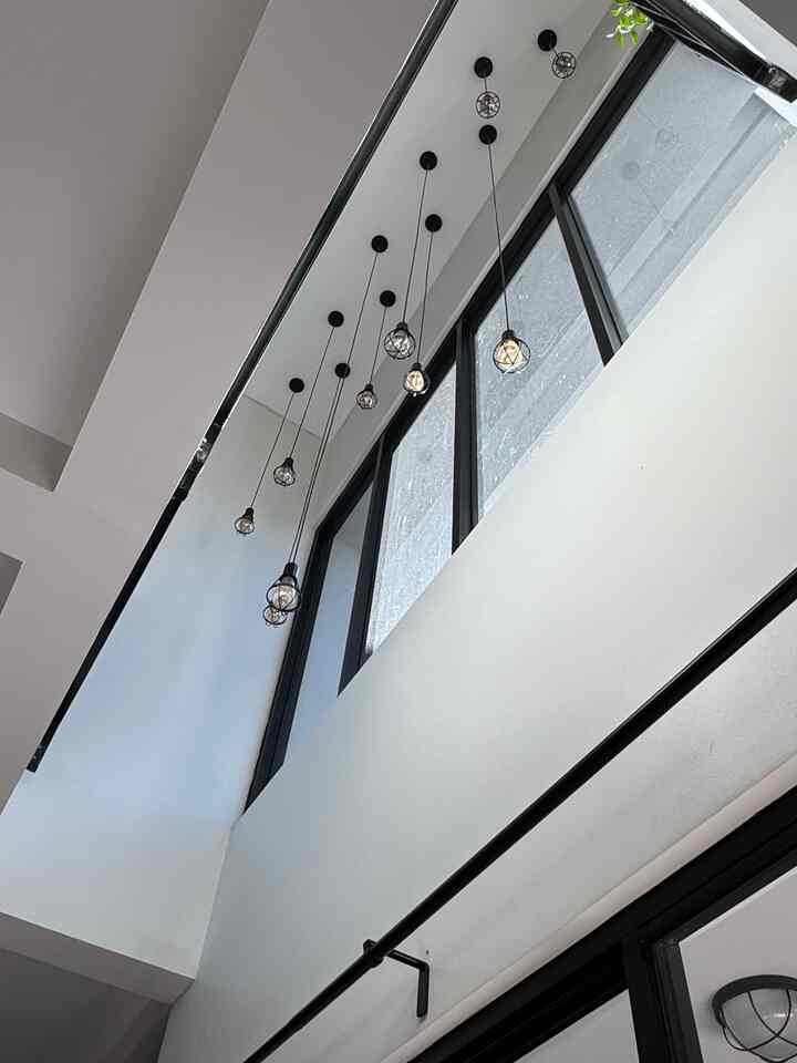 White walls and black framed windows featuring vintage-style pendant lights in a narrow, long void space