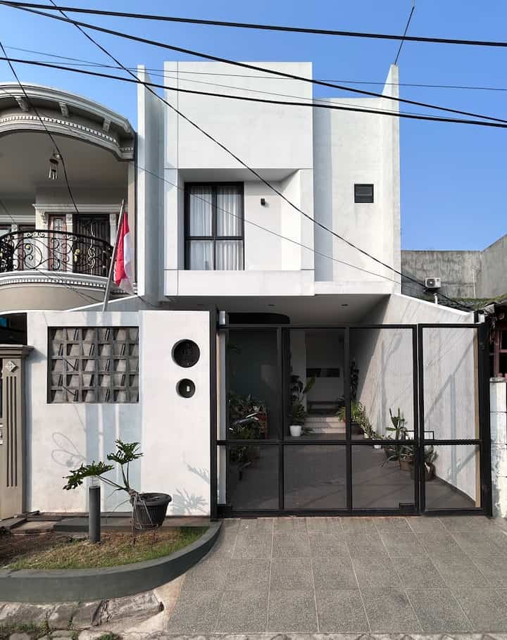 Pagar dibuat dengan warna senada dengan badan bangunan, yaitu permainan dinding cement washed kombinasi roster exposed, cat putih, dan warna hitam gerbang pagar yang terbuat dari besi hollow dan expanded metal.

Pada bagian tengah terdapat 2 lingkaran yang mejadi elemen unik di desain pagar kami. Terinspirasi dari pengulangan bentuk geometri yang memang kami terapkan untuk desain. 

Lingkaran atas untuk nomor rumah yang terbuat dari plat besi, dan lingkaran bawah sebagai tombol bel untuk tamu.

Gerbang pagar untuk masuk mobil menggunakan sliding dan 1 pintu swing untuk keluar masuk orang. Terdapat 2 kotak lubang untuk tempat masuknya tangan untuk membuka dan menggembok gerbang. 

Total lebar dibagi dua area dinding 2,5 m dan area gerbang 3,5 m karena kami siapkan juga untuk space masuk motor di samping.

#PagarMinimalis #PagarRumahMinimalis #PagarMetal #PagarRoaster #DindingPagar #InspirasiPagar #PagarStyle #Gate #HouseGate