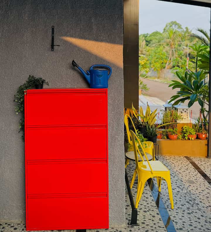 Red shoe cabinet and yellow outdoor chairs on a balcony with various plants creating a lively atmosphere