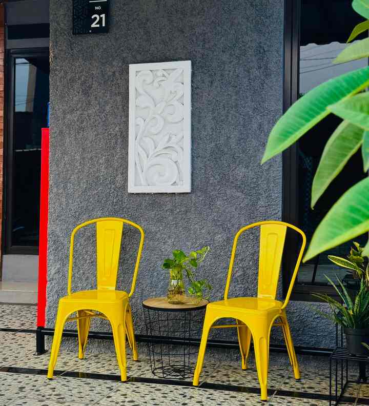 Yellow chairs and a small side table in a cafe style terrace with decorative plants