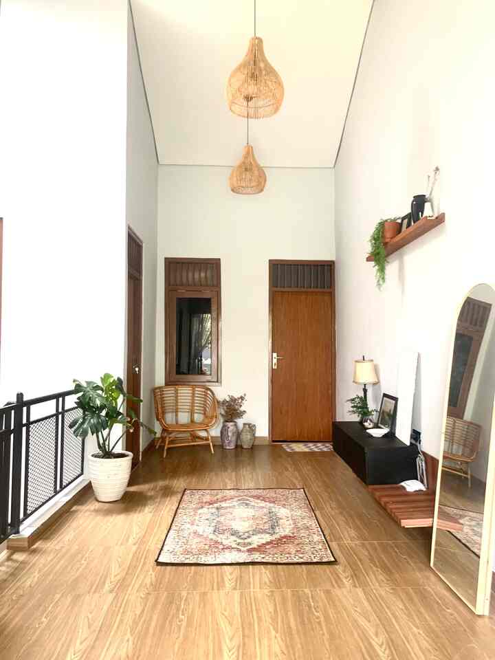 Natural wood tone entrance space with beige carpet, rattan pendant lights and plants creating cozy atmosphere