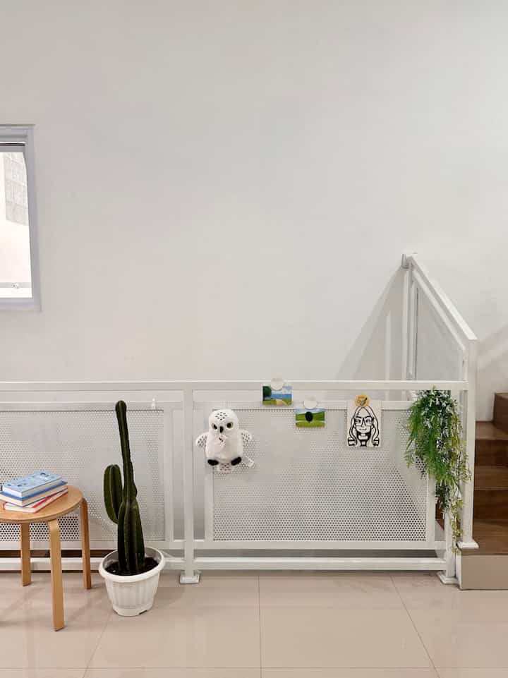 A bright, clean entrance space with white background, wood-toned staircase, and green plants