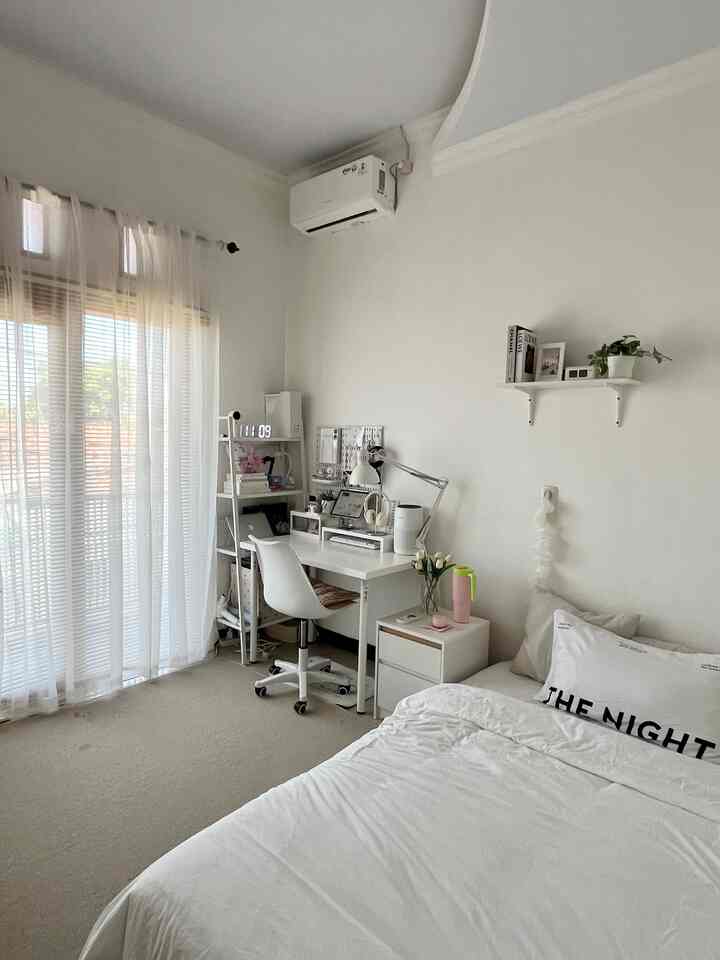Bright white and natural-tone bedroom featuring sliding glass door and workspace desk with overall clean atmosphere