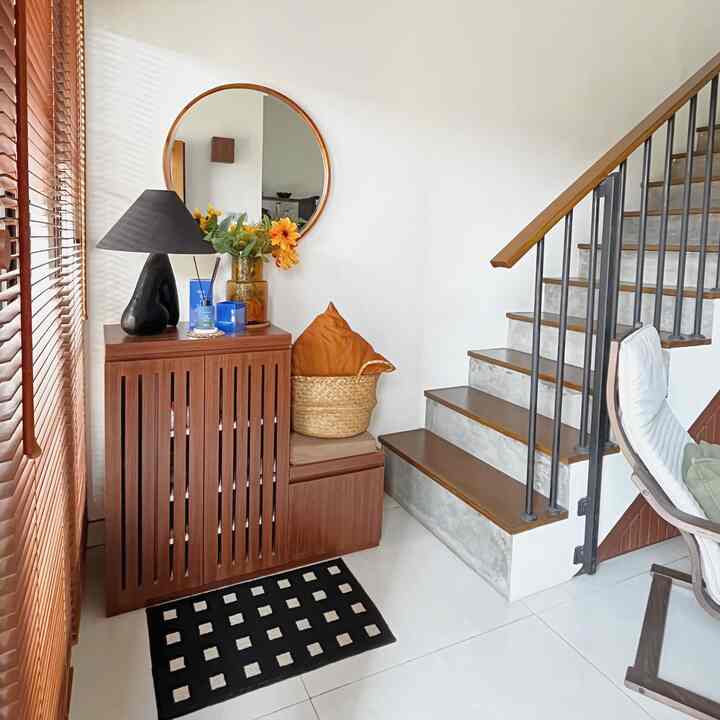 White-walled entrance and living area featuring wood-toned furniture, a round mirror, and floor lamp creating a natural atmosphere