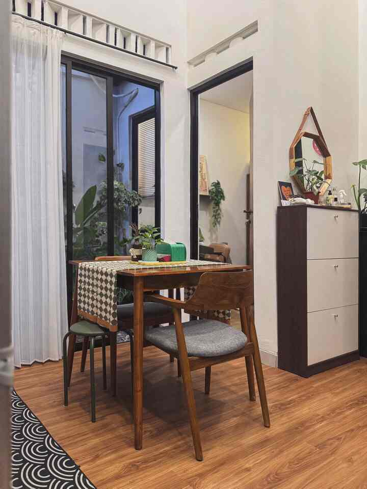 Beige and wood tone dining room featuring wooden table and chairs, checkered tablecloth, and plants arranged in a cozy setting
