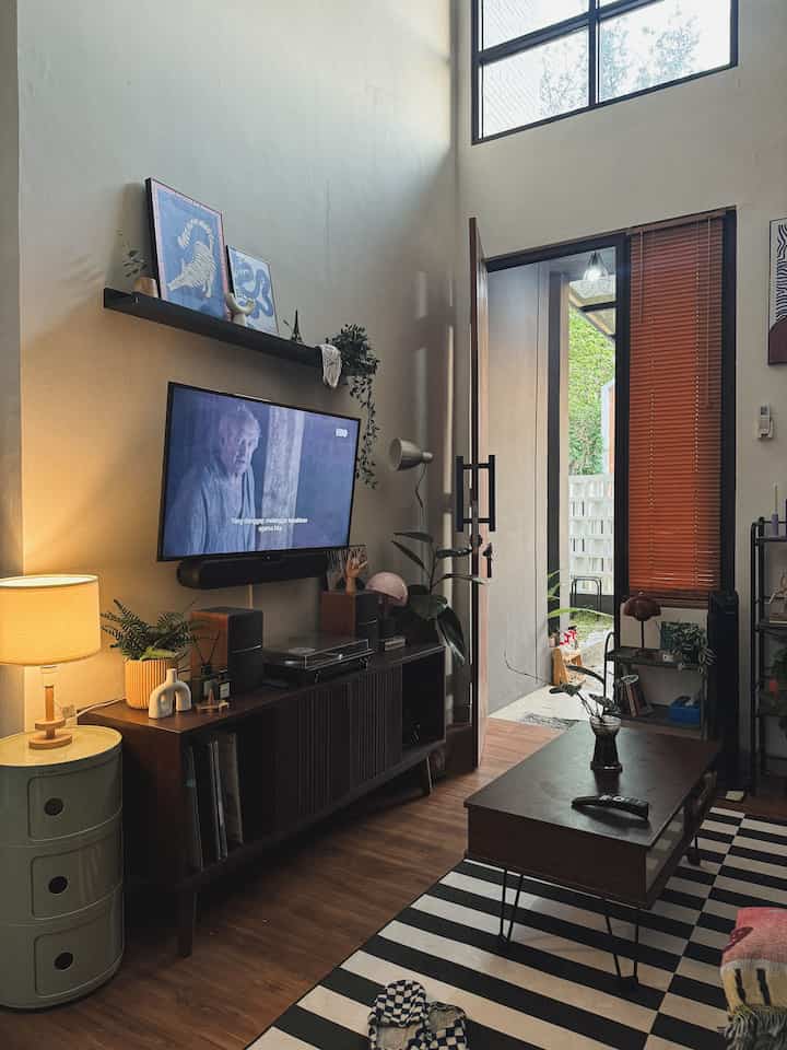 Cozy living room with white walls and wood tone furniture, featuring a TV and coffee table in a compact space
