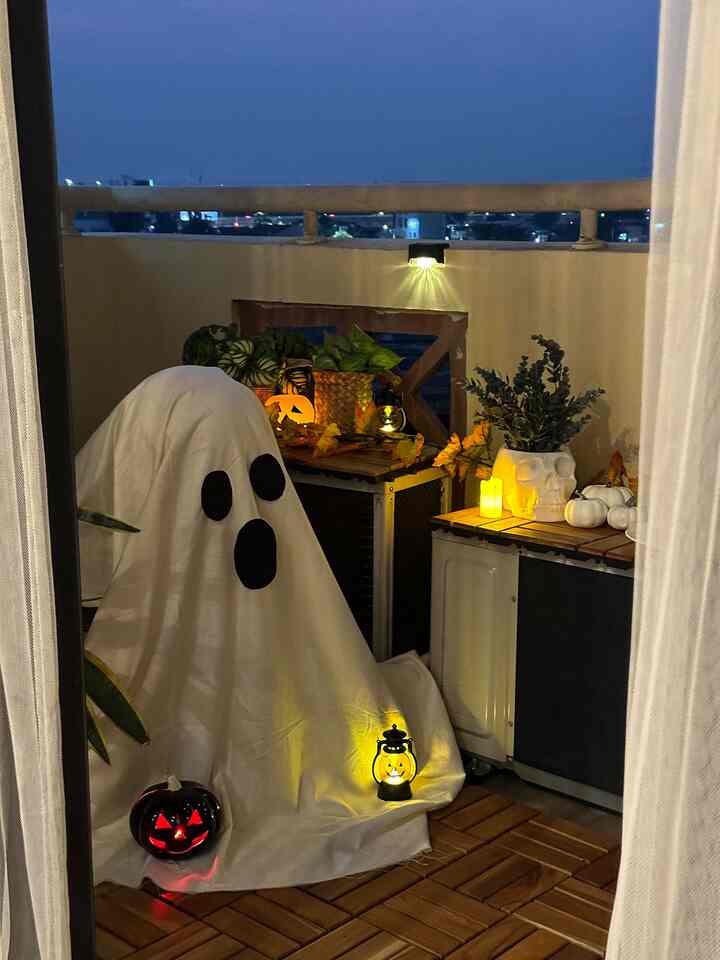 Wood tone deck balcony at night featuring white and orange Halloween decorations with warm lighting