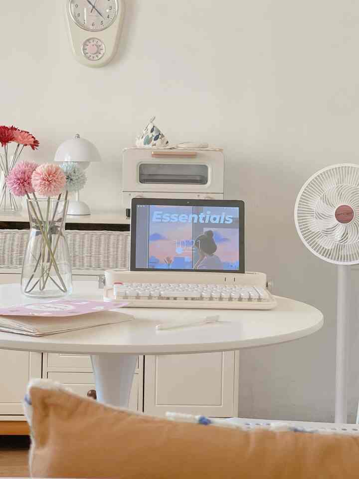 Ivory and white toned living room featuring a round table with retro keyboard and tablet, presenting a simple space