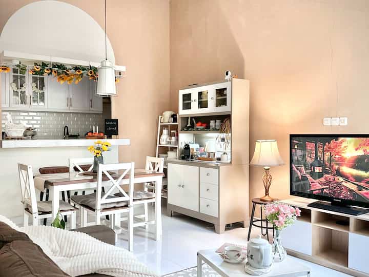 White and beige toned dining room and living room featuring dining table and sofa in cozy natural modern space