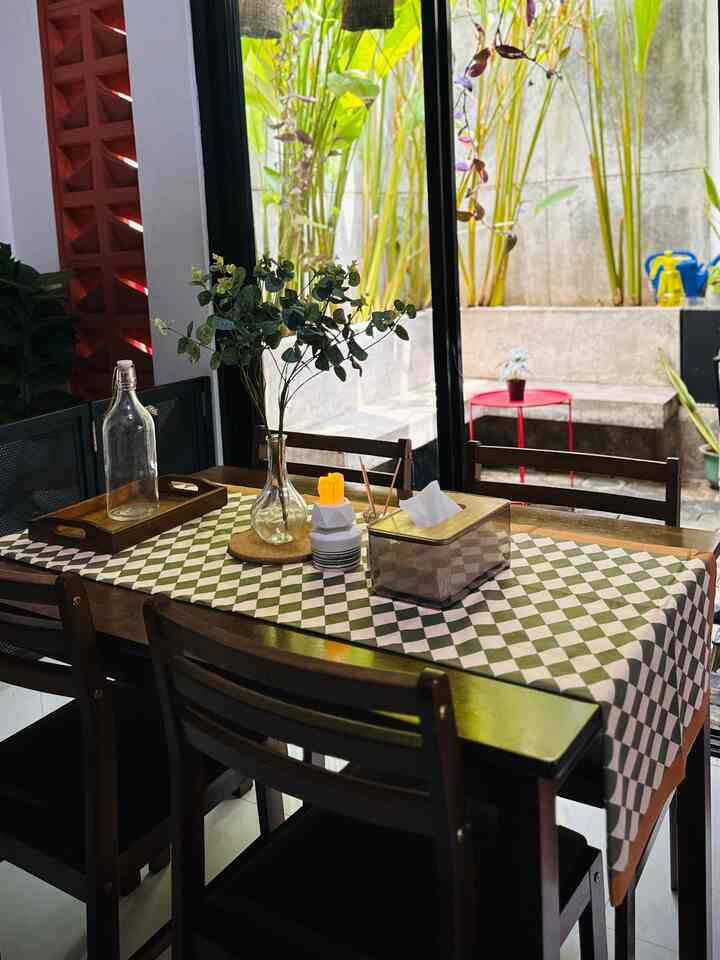 Brown wood-toned dining room with green plants and checkered table runner, creating a natural and cozy atmosphere