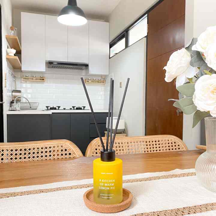 White and brown toned kitchen featuring a wooden dining table with a diffuser and flowers creating a natural and warm atmosphere