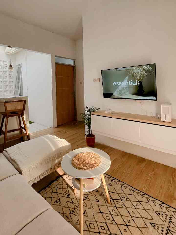 Modern living room with white walls and wood tone floors, featuring a sectional sofa and patterned carpet creating a cozy atmosphere