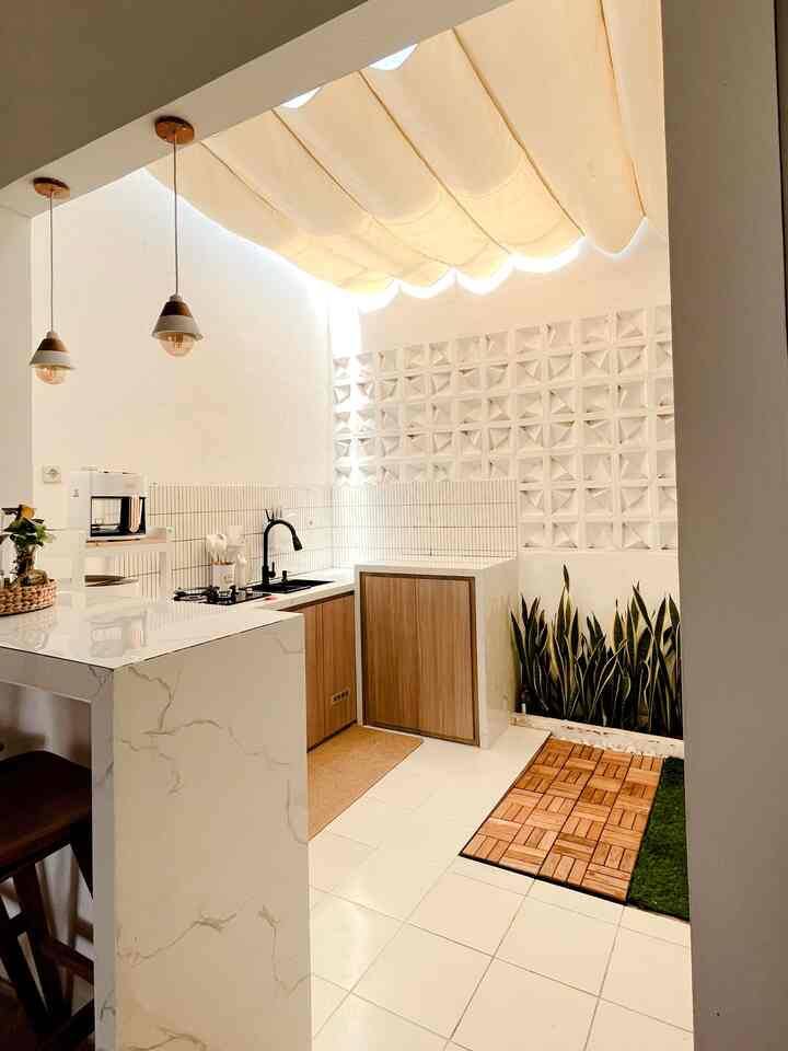 Bright white and natural wood tone L-shaped kitchen featuring plants and natural light with a modern, clean interior