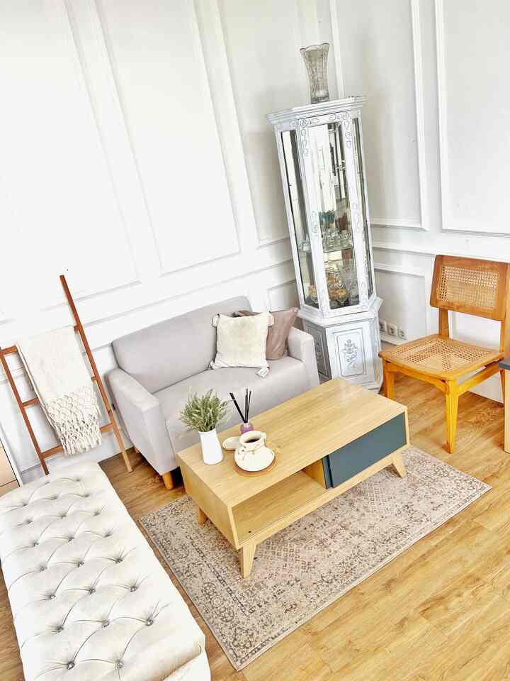Natural toned living room featuring gray sofa, wood tone coffee table, beige carpet, and a display cabinet in a simple Scandinavian style