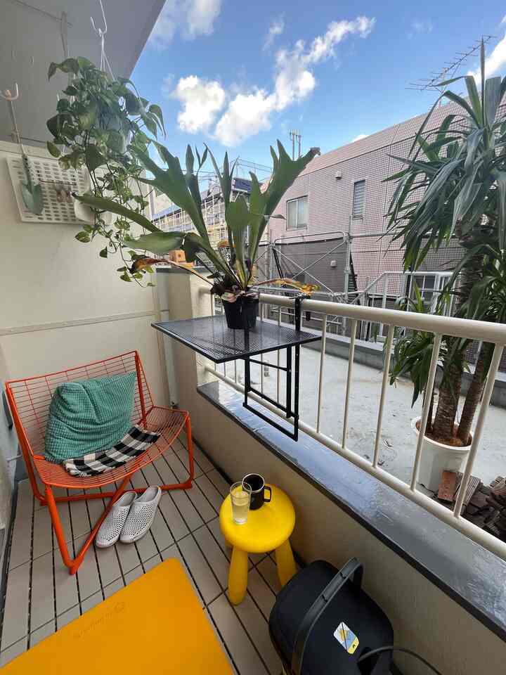 Yellow and black toned balcony featuring an orange outdoor chair and abundant plants in a cozy atmosphere
