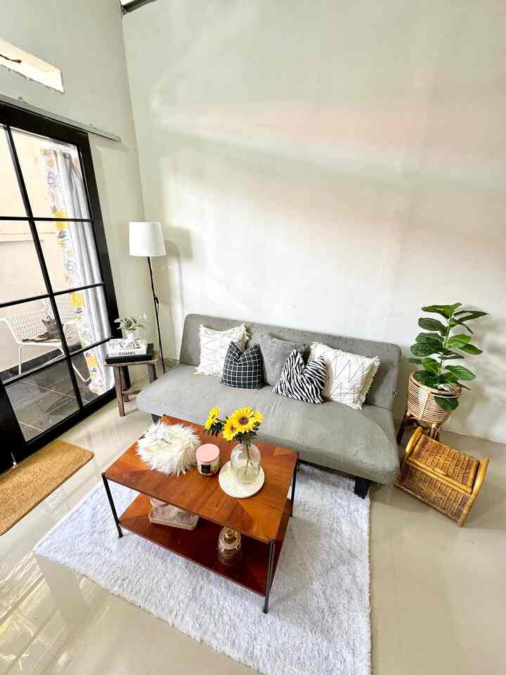 White and gray toned living room featuring a sofa bed, coffee table, and floor lamp in a simple, natural setting