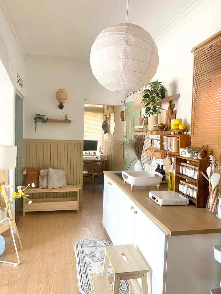 Natural tones and white walls define a kitchen space featuring wooden furniture and storage shelves with a cozy atmosphere