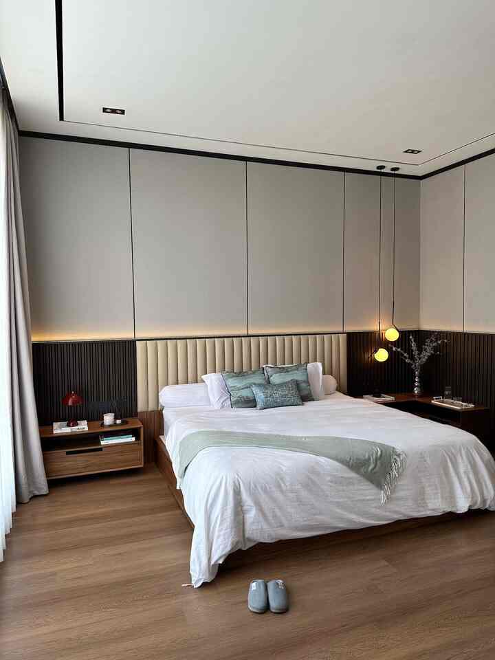 Welcome to JEAN HOUSE master bedroom! Ini adalah ruangan favorit aku karena ini ruang tidurku 🥰

Aku memilih gaya minimalis modern dengan sentuhan mewah (luxury minimalism). Gaya ini memberikan kesan yang bersih, rapi, dan elegan. Selain itu, gaya ini juga menekankan pada fungsi dan kepraktisan, namun tetap memberikan sentuhan elegan yang membuat ruangan terasa nyaman dan mewah.

Aku menerapkan gaya ini di kamar tidur utama dan lemari pakaian atau walk-in closet. Di kamar tidur, perpaduan antara panel dinding dengan warna netral, furnitur kayu, serta pencahayaan yang tepat membuat suasana ruangan terasa nyaman dan elegan.

Elemen utama yang aku gunakan adalah:
	•	Material: Panel dinding kayu dan headboard berlapis kain lembut yang memberikan tekstur pada ruangan.
	•	Furnitur: Meja samping tempat tidur dari kayu, lemari pakaian dengan pintu kaca transparan, serta rak kaca untuk pajangan tas dan aksesori.
	•	Barang dekoratif: Lampu meja merah yang memberikan sentuhan warna, diffuser, dan vas bunga kering untuk mempercantik tampilan.

Untuk mencapai tampilan minimalis modern dengan kesan mewah, berikut beberapa tips yang bisa saya bagikan:
	•	Pilih palet warna netral: Warna netral seperti beige, cokelat, dan putih memberikan kesan yang tenang dan rapi.
	•	Gunakan material berkualitas tinggi: Material seperti kayu dan kaca membuat tampilan ruangan terlihat lebih elegan.
	•	Tambahkan sentuhan dekorasi sederhana namun ikonik: Seperti lampu meja unik atau barang dekorasi yang memiliki warna kontras untuk memberi karakter pada ruangan.
	•	Manfaatkan pencahayaan ambient dan aksen: Lampu tersembunyi di dalam lemari atau di balik panel dinding dapat menciptakan suasana hangat dan mewah.
	•	Minimalisir barang yang tidak diperlukan: Jaga agar ruangan tetap rapi dan fungsional dengan tidak menempatkan terlalu banyak barang, sehingga menciptakan suasana yang lapang dan nyaman.

#lamputidur #lampugantung #bantalsofa #cushion #vase
#rumahminimalismodern #rumahminimalis
#rumahmodern #rumahcontemporary #minimalist #contemporary #modern #luxury
