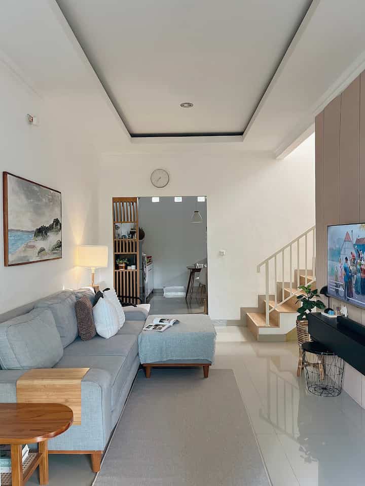 Modern minimal living room in bright white and gray tones, featuring a large gray sofa and floor lamp creating a cozy atmosphere