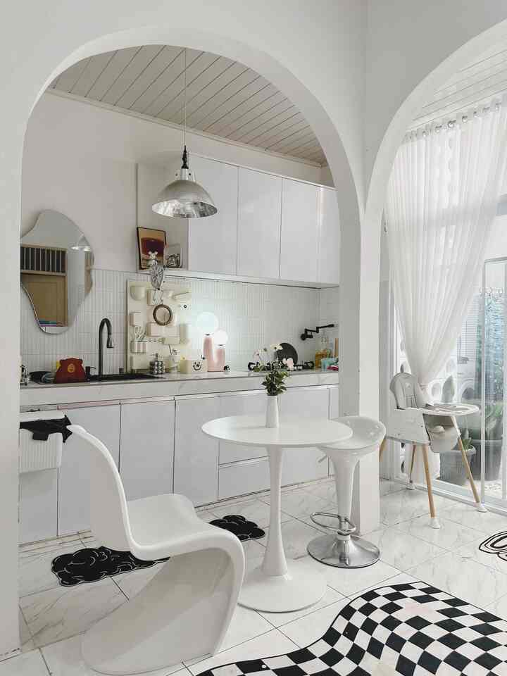 Ruang ini saya namakan Arch Kitchen. Berawal dari renovasi membuka dinding sekat dapur lama menjadi dinding terbuka berbentuk melengkung pada bagian atas. Nuansa serba putih menjadikan dapur ini terlihat luas dan bersih. Sentuhan dekorasi furniture kursi panton, meja bundar dan kursi bar semakin terlihat estetik. 
Pada kitchen cabinet dihiasi frame, jam, tempat tusuk gigi dan garpu buah berbentuk bear warna silver. Dan pada top table tersedia aneka printilan lucu seperti talenan sanrio head, tissue box, botol sabun material keramik. 
Untuk lighting dipasang lampu gantung bergaya retro. #dapurmodern #dapurcantik #smeg #kursipanton #mejabundar #kursibar #botolkeramik #tissuebox #kesetdapur #talenansanrio #jamdindinghias #wallpockets #frameestetik #lampugantung #dapurminimalismodern #ummaarrayyan #ummaHaus #ohouseseason9 #kitchenset #kitchensetminimalis #mejamakanminimalis #peralatanmakan #inspirasiruangmakan