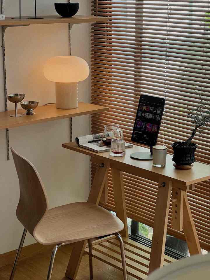 Natural wood-toned efficient home office featuring desk, chair, lamp, and plant in a simple workspace