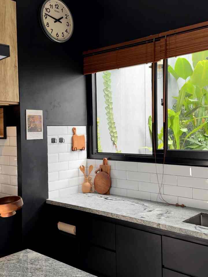 Black and white kitchen space with wood tones, featuring a large window and neatly arranged kitchen utensils creating a sleek atmosphere