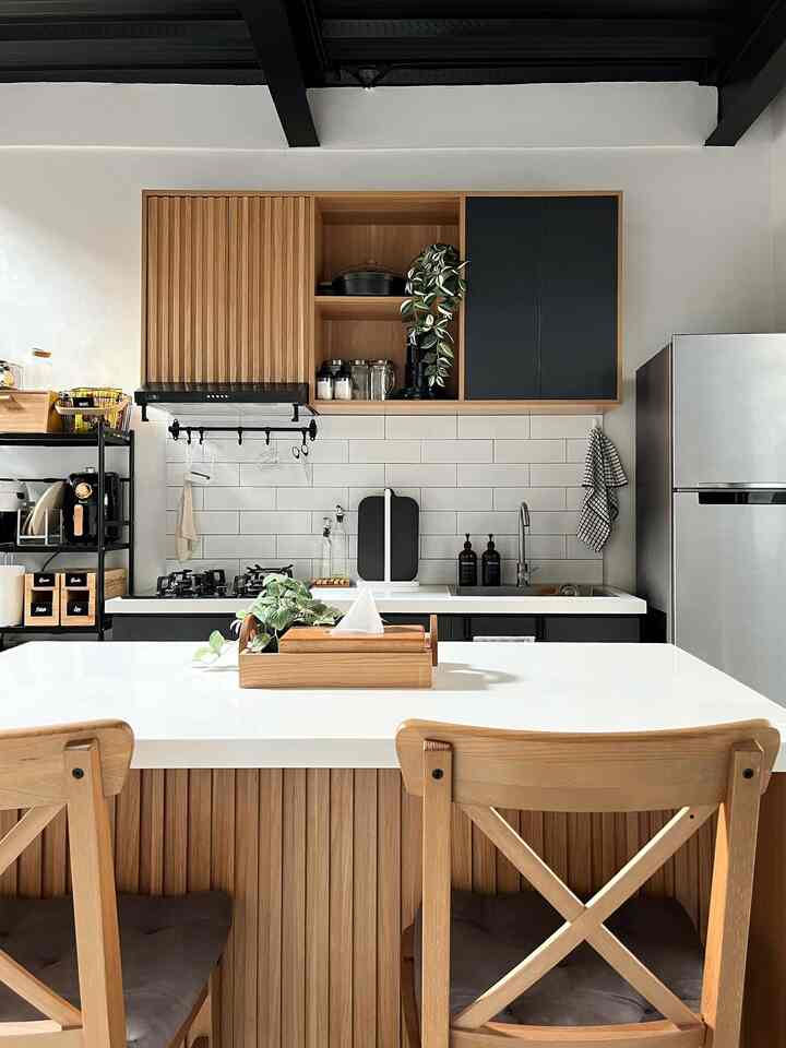 White and wood tone kitchen with black industrial elements and dining chairs, featuring a modern and warm atmosphere