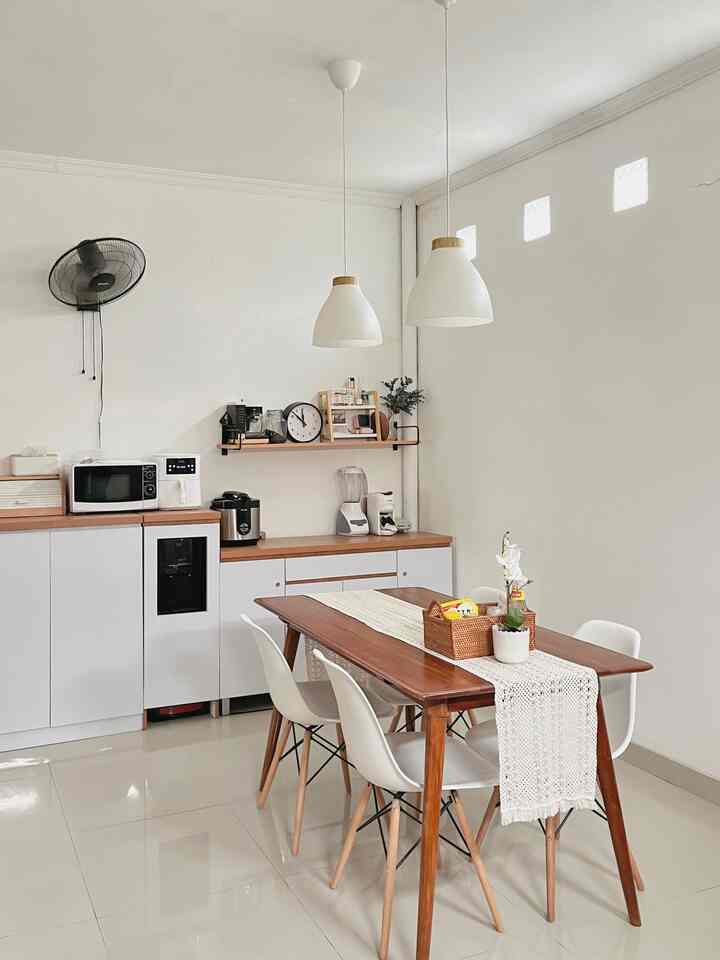 A simple and cozy dining room with white walls and natural wood tone dining table, featuring pendant lights and storage shelves as highlights