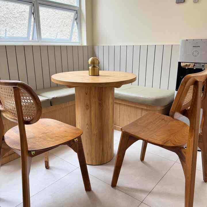 Wood tone and beige breakfast nook featuring round dining table and rattan chairs in a cozy setting