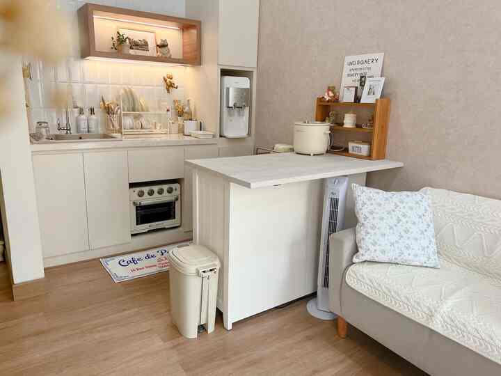 White and ivory toned compact kitchen and living area featuring a sofa bed and kitchen island in a vintage cafe-inspired interior