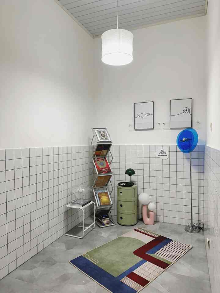 Small white-toned room featuring metal bookshelf and colorful rug with a modern atmosphere