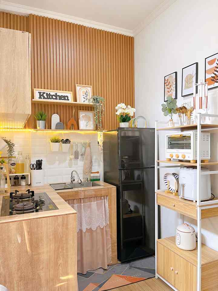 Compact kitchen featuring wood tones and white walls, organized storage spaces with modern appliances in a clean, minimal design