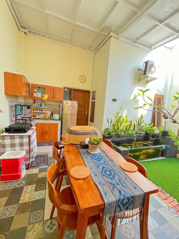 Natural wood tone kitchen and dining room featuring green carpet, plants, and an aquarium, creating a cozy atmosphere